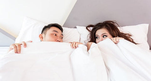 A couple peacefully resting in bed, surrounded by soft white sheets, exuding warmth and intimacy
