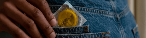 A person discreetly holds a condom in their pocket, emphasizing safe practices and personal responsibility.
