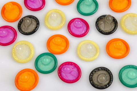 A collection of colorful condoms arranged neatly on a white surface, showcasing a variety of vibrant hues.